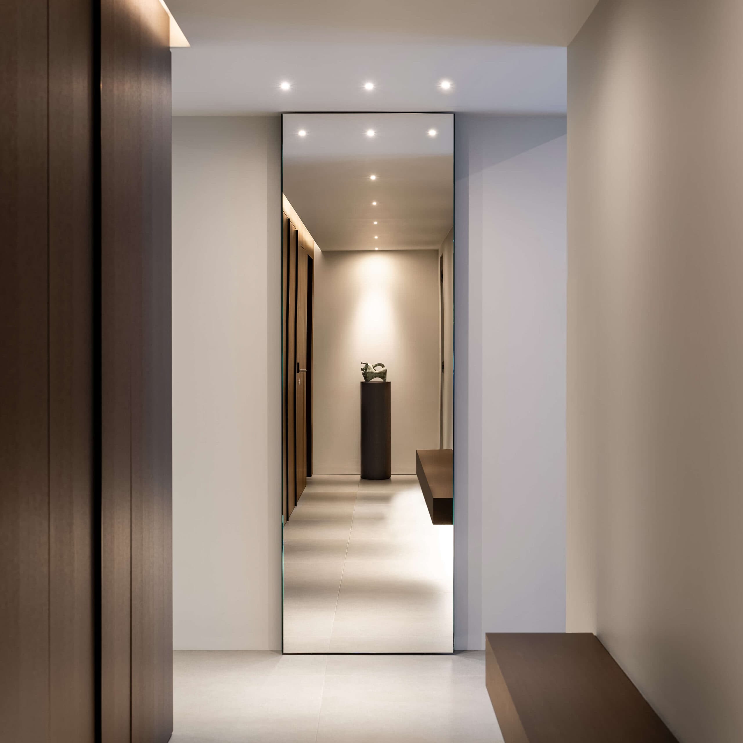 Corridoio della villa con specchio a tutta altezza e volumi in rovere